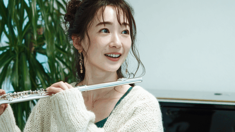 フルートを持って話す女性