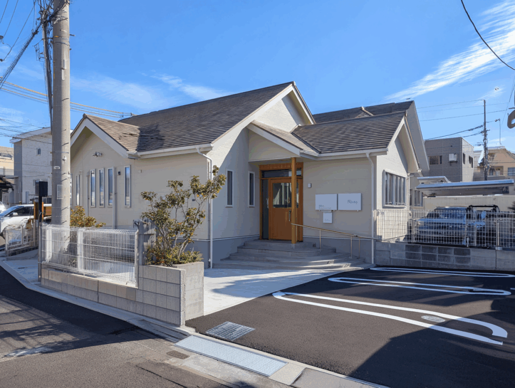 新しい時代の小児科へ ― 建て替えとリニューアル 3年前、これまでの場所に新しい建物を建て、クリニックは新たに生まれ変わりました。 木のぬくもりを感じられる優しい空間にこだわり、「子どもが怖がらない小児科」 を目指して設計しています。 明るい日差しが差し込む待合室や、木の家具と温かみのある色合いが、来院する親子に安心感を与えています。 「子どもたちが怖がらない小児科」 建て替えの際に大切にしたのは、「子どもたちが怖がらない小児科」をつくること。 病院というと、どうしても「白くて無機質」「痛いことをされる場所」というイメージを持つお子さんも多いもの。 そこで新しい建物では、木のぬくもりを感じる素材をふんだんに使用し、やさしいパステルカラーを基調とした空間デザインに仕上げました。 待合室は日差しがやわらかく差し込み、木の香りがほんのり漂う、まるで「おうち」にいるような安心感に包まれています。 診察前の不安な時間も、親子で穏やかに過ごせるように。 そんな想いを込めて、空間づくりに細やかな配慮を重ねました。 充実した設備で安心・快適な診療を また、安心して通院していただくために、新しいクリニックには、 発熱者専用の個室待合室(感染症対策を徹底) 授乳室・おむつ交換台完備(小さなお子さま連れでも安心) バリアフリー設計(ベビーカーや車いすでもスムーズに移動可能) など、さまざまな設備を整えました。 発熱のあるお子さま専用の個室待合室を設け、他の患者さまとの動線を分けることで、より安全な環境を確保しています。 授乳室やおむつ交換台も完備しており、小さなお子さまをお連れの保護者さまにも快適にお過ごしいただけます。 さらに、バリアフリー設計を採用しているため、ベビーカーや車いすの方もスムーズに移動が可能です。 どなたにとっても「やさしい」小児科であることを目指し、細やかな思いやりを建物のすみずみに込めました。 子どもたちの反応 ― リニューアル後に生まれた笑顔 リニューアル後、私たちスタッフが何よりうれしかったのは、子どもたちの表情が明るく変わったことです。 以前は診察室に入ると泣き出してしまうお子さんも多く見られましたが、今では「木のおうちみたい!」「かわいい色だね!」と、笑顔で手を振って入ってきてくれる子が増えました。 やわらかな木の壁やパステルカラーの空間が、子どもたちの緊張をやさしくほぐしてくれているようです。 待合室のキッズスペースでは、絵本を読んだり、積み木をしたりしながら過ごす姿も見られます。 また、診察が終わったあとに「また来るね!」と笑顔で帰っていくお子さんも増え、“病院=こわい場所”から“安心できる場所”へと変わりつつあることを日々感じています。 保護者の方からも 「以前より子どもが落ち着いて診察を受けられるようになった」 「病院に行くのを嫌がらなくなった」 といったお声を多くいただいています。 この変化こそが、私たちが建て替えに込めた思いの成果だと感じています。 これからも“子どもが笑顔で通える小児科”として、地域に寄り添いながら歩み続けてまいります。 これからも、地域の子どもたちと共に 創業から数十年。 変わらずこの地に根ざし、「子どもたちの笑顔と健やかな成長を見守るクリニック」であり続けることが、私たちの願いです。 これからも、地域の皆さまと共に歩みながら、より安心できる小児医療を提供してまいります。